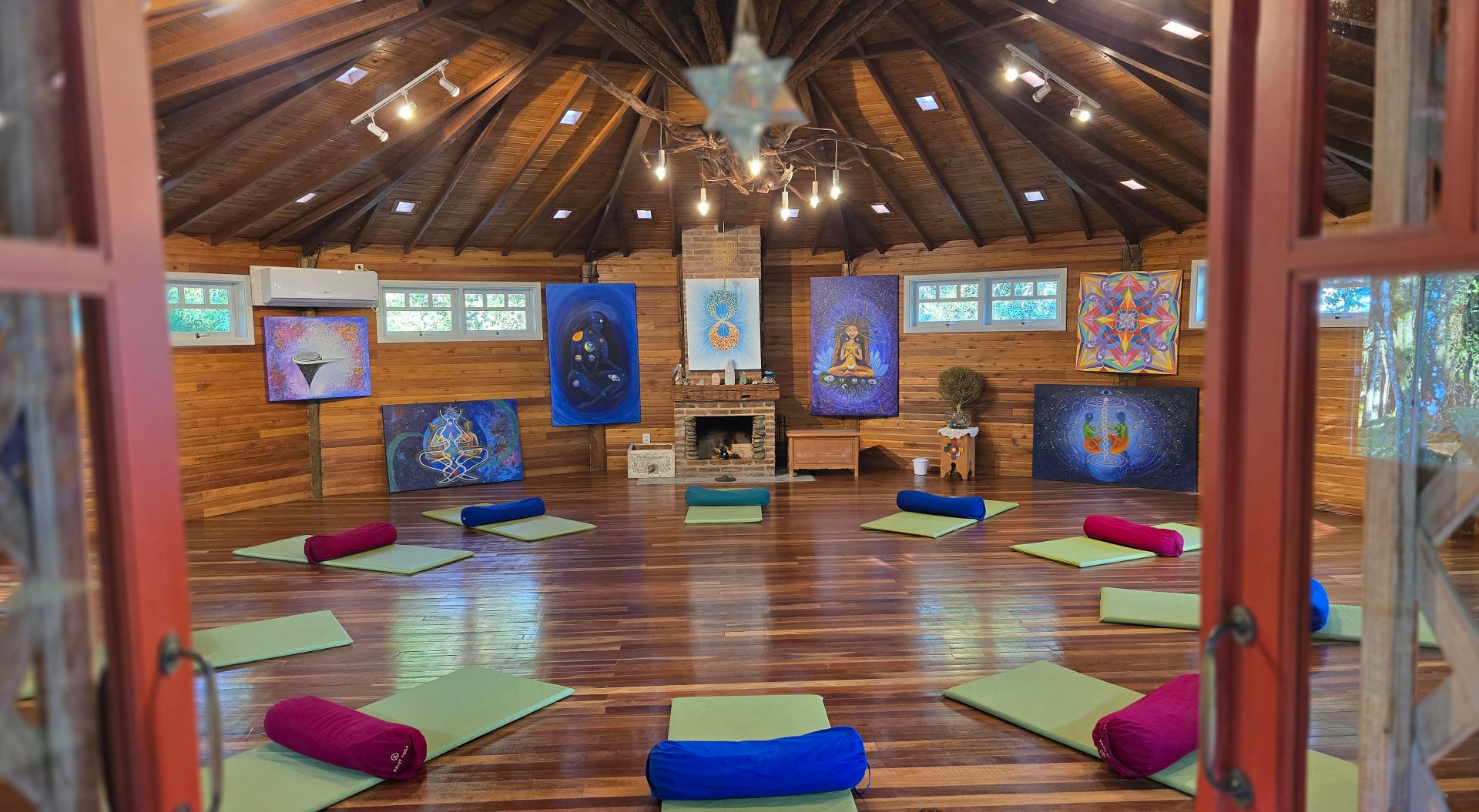 Templo Flor e Ser: sala circular de madeira com almofadas e mandalas