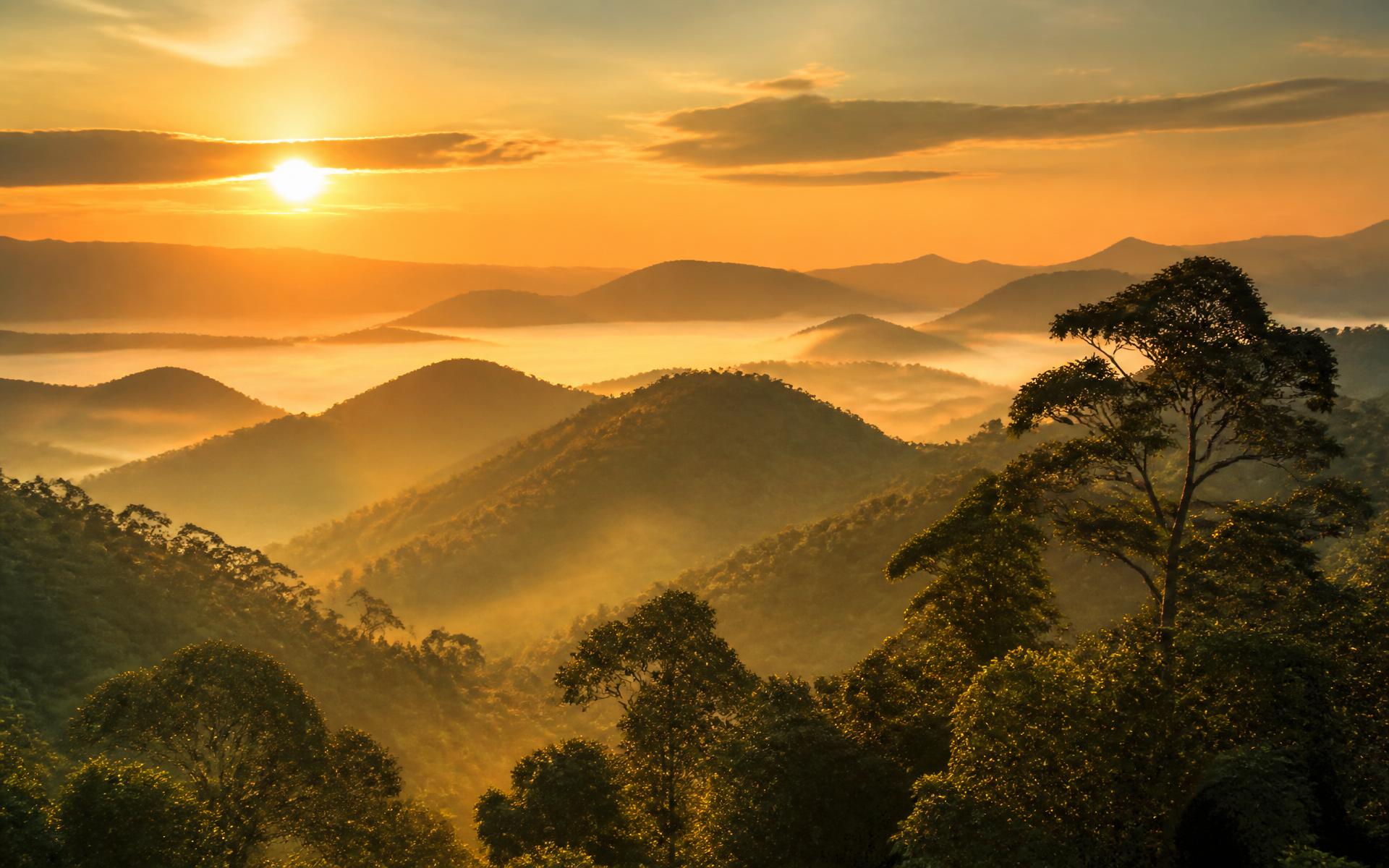 Pôr do sol sobre montanhas verdes cobertas de mata